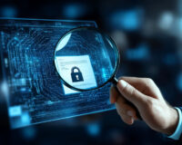 Magnifying glass highlighting a digital padlock on a glowing blue circuit board, symbolizing cybersecurity analysis and threat intelligence.