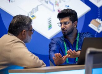 Two professionals in discussion at the PDI Technologies booth during NACS Show 2025 in Chicago.