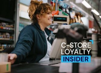 Smiling convenience store cashier helping a customer, representing C-store loyalty and tobacco loyalty engagement strategies.