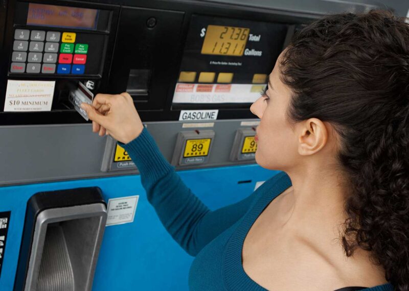 young woman paying with credit card at gas pump