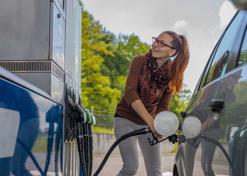 Customer refueling vehicle at a convenience store gas station, highlighting fuel market trends.
