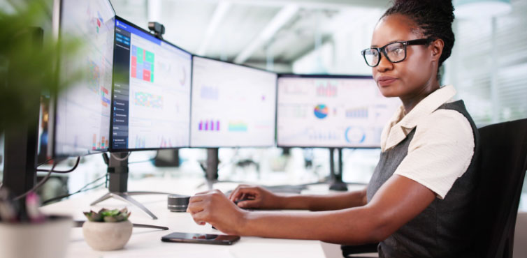 Business professional reviewing loyalty analytics and performance dashboards on multi-monitor setup