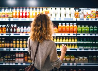 A shopper selecting beverages from a refrigerated display in a convenience store