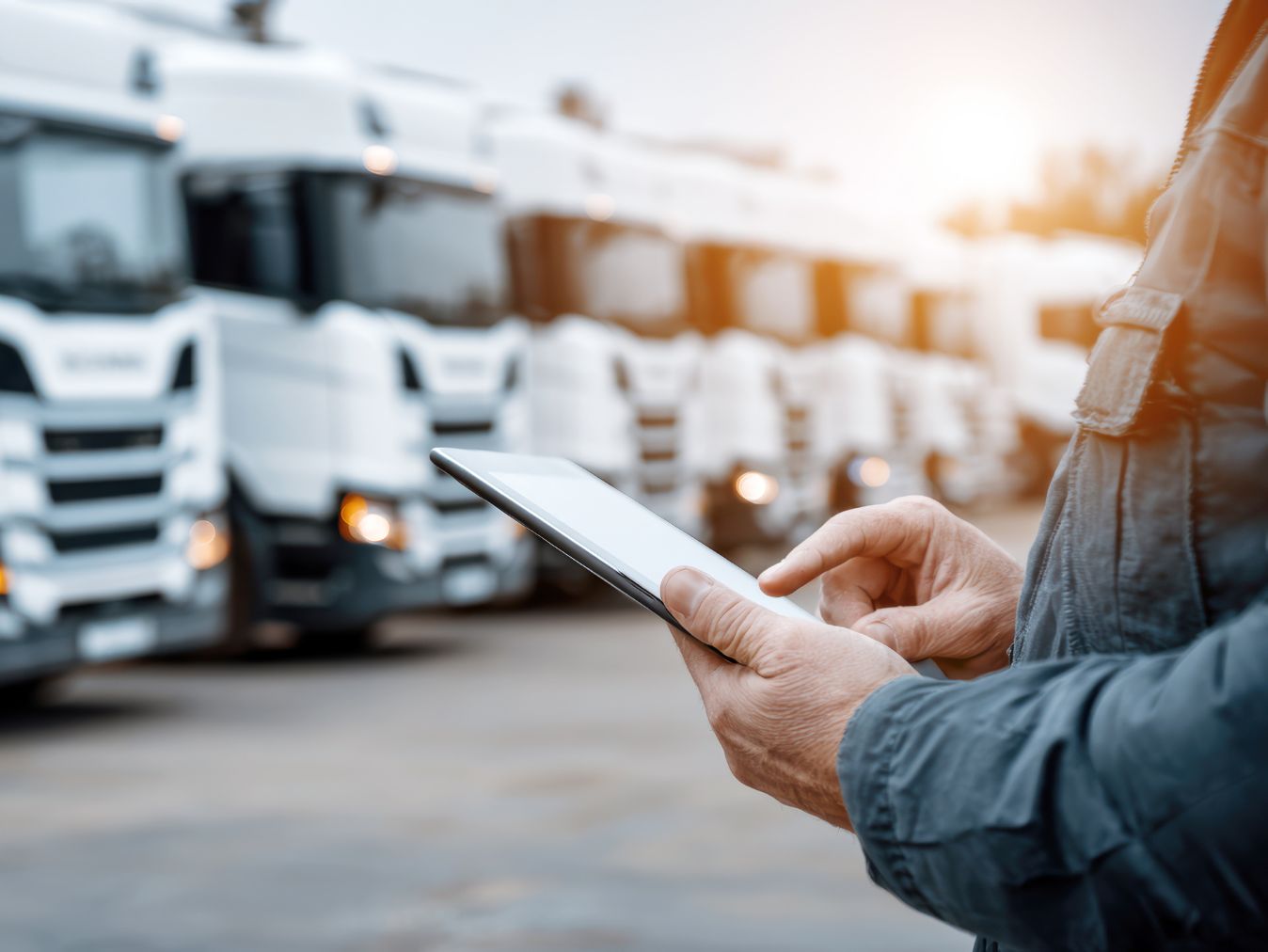 Fleet manager using tablet to monitor commercial trucks at fleet yard