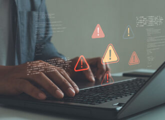 Cybersecurity threat alerts appearing on a laptop screen as a user types, representing malware detection and cyber risk monitoring.