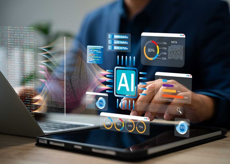 Business leader using a laptop and tablet with floating AI-powered dashboards, data analytics charts, and search interfaces displayed above the devices