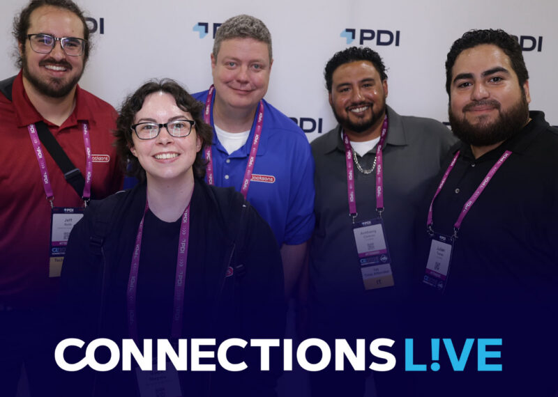 Five smiling Connections Live attendees wearing PDI lanyards and event badges, posing together in front of a PDI-branded backdrop.
