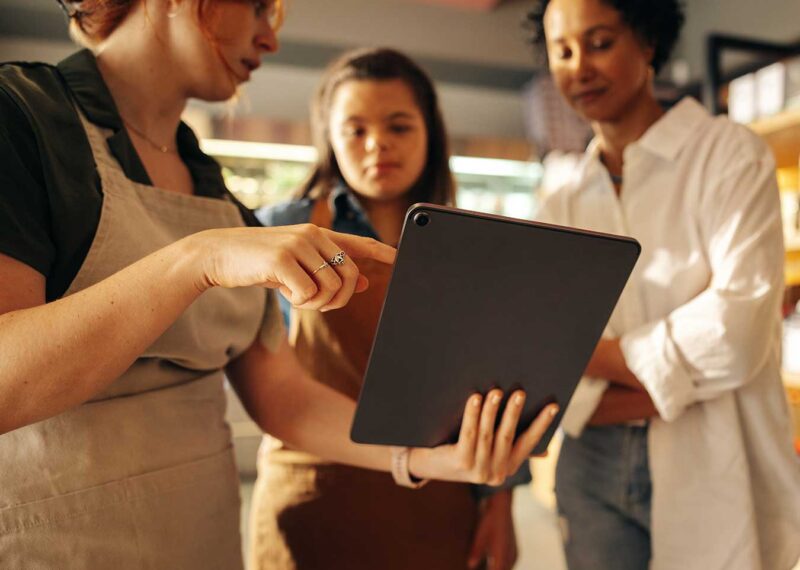 Convenience store staff reviewing information on a tablet together in the store.