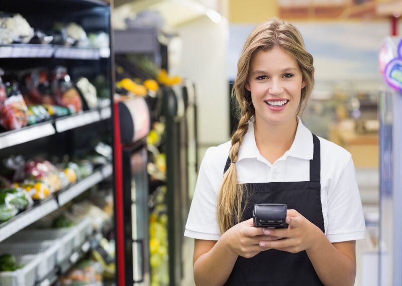 Female convenience store clerk scanning products on shelf with handheld scanner