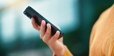 Close-up of a hand holding a smartphone displaying a mobile app