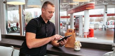 Convenience store customer using a tablet at the counter while drinking coffee