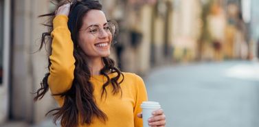 Woman smiling while holding her phone outdoors, representing repeat customer engagement